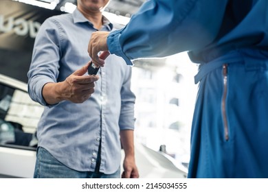 Asian automotive mechanic repairman handing car remote key to client. Vehicle service manager give the key back to car owner after successful of checking and maintenance car engine in mechanics garage - Powered by Shutterstock