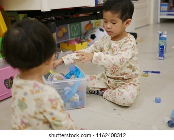 Asian Baby, 31 Months Old, (right) Is Cleaning Up / Putting Away Toys She Played With Her Little Sister