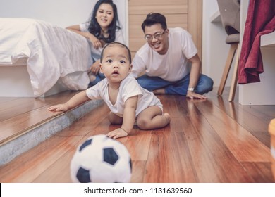 Asian Baby Boy Crawl On The Wooden Floor Over The Father And Mother In The Bedroom,Family Lifestyle Concept