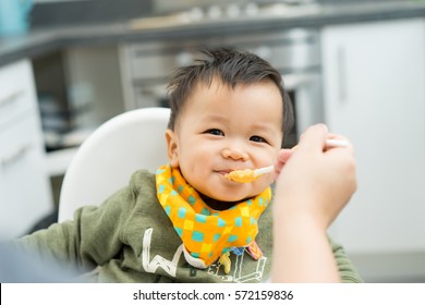 Asian Baby Boy Eating Blend Food On A High Chair