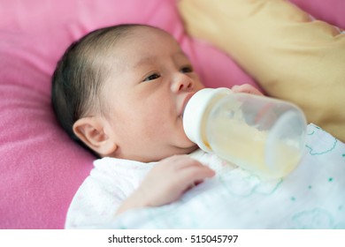 Asian baby boy infant eating milk from bottle.
