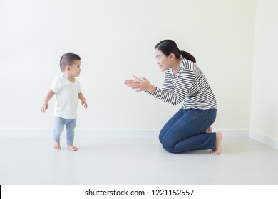 Asian Baby Boy Learning To Walk With Watching And Take Care By Mom, Son Take First Steps At Home