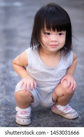 Asian Baby Child Girl be constipated. She wearing a gray Sleeveless tank top shorts. The face is crying red eye. She squat on the road around the house in the evening. Baby aged 2 years and 4 months.