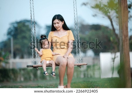Asian baby daughter with mother wearing yellow dress in the park. Happy loving family. mother playing with her baby. Kid and mom are playing on the nature outdoors. Walk in the park.