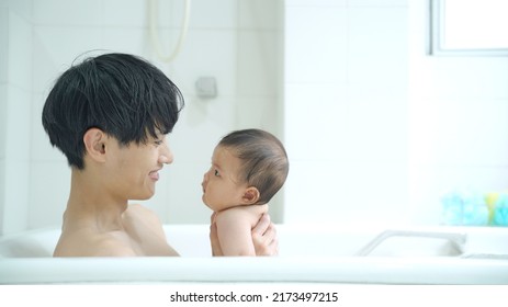 Asian Baby And Father In Bathroom. Child Rearing. Newborn.