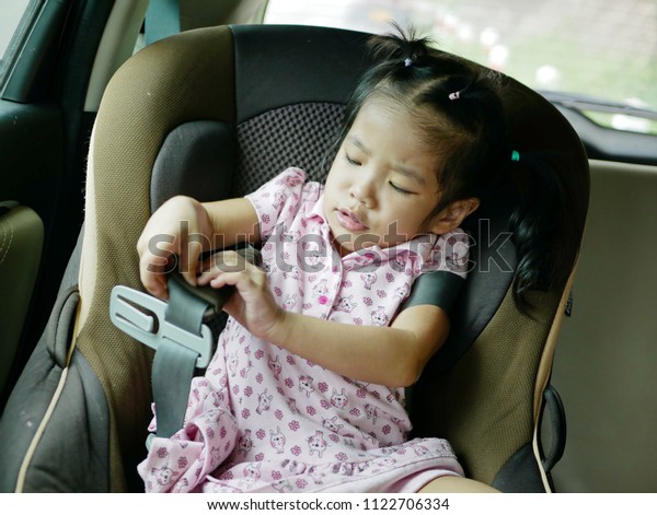 Asian baby girl, 30 months old, being frustrated\
and struggling to put on a safety belt - allowing baby to be\
frustrated, not helping them too quickly, to let them learn about\
their own emotions