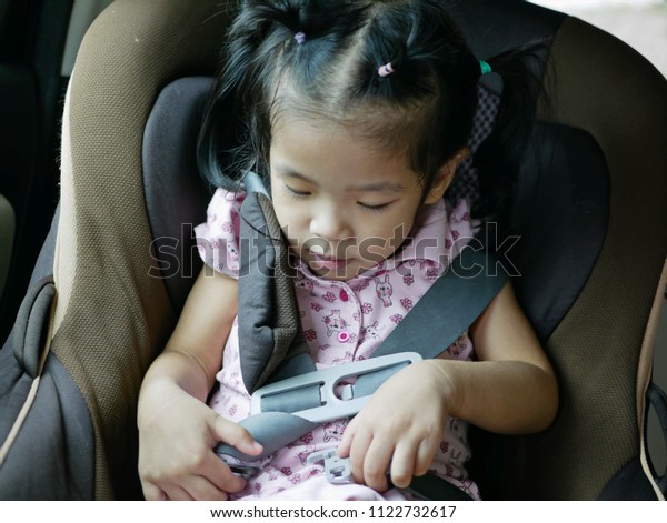 Asian baby girl, 30 months old, learning to\
put on a safety belt by herself - helping baby build a good driving\
habits by starting in the car\
seat