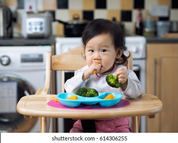 Asian Baby Girl Eating Vegetable At Home Kitchen