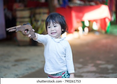 The asian baby girl playing a wood gun.She very happy and fun.