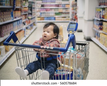 Asian Baby Girl In Shopping Trolley  In Supermarket