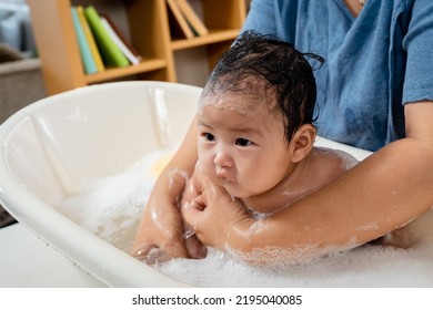 Asian Baby Girl, Taking A Bath, He Bathes In A Bubble Bath, With A Single Mother Bathing Her Daughter, Gently, The Daughter's Face And Body Were Filled With Bubbles.