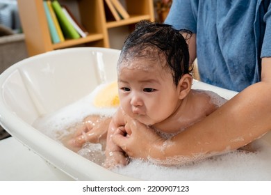 Asian Baby Girl, Taking A Bath, He Bathes In A Bubble Bath, With A Single Mother Bathing Her Daughter, Gently, The Daughter's Face And Body Were Filled With Bubbles.