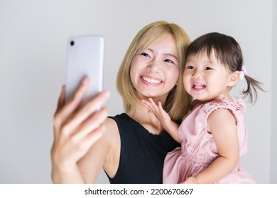 Asian Baby Girl With Young Mother Taking Selfie