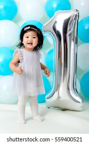 Asian Baby Girl's First Birthday With Shiny And Blue Ballons