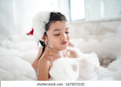 Asian Baby Kid Bathing Concept. Adorable Girl In Bathtub With Fluffy Soap Bubble.