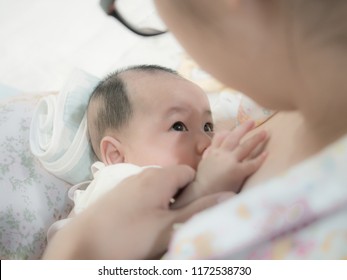 Asian Baby Look At Mom While Get Breastfeeding. Mother Is Breastfeeding Her Child.