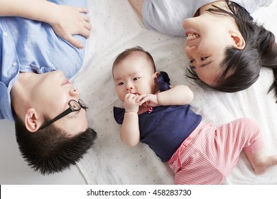 Asian Baby With Parents, Lying In Bed Comfortable