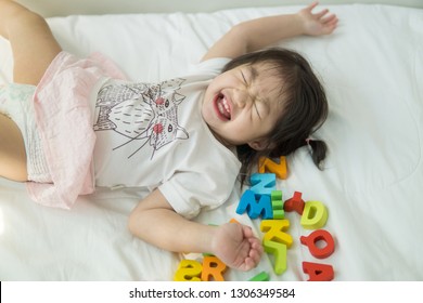 Asian Baby Playing ABC Letters On A Bed