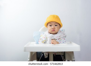 asian baby sitting in high chair white background,baby angry