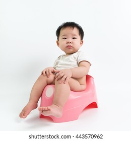 Asian Baby Sitting On Potty Over White Background