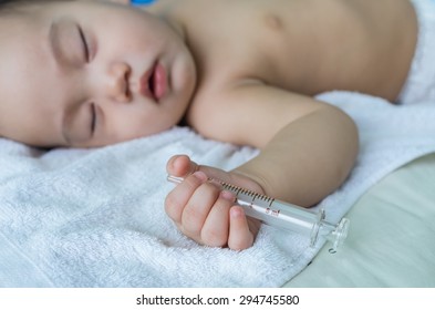 Asian baby sleeping and holding the syringe