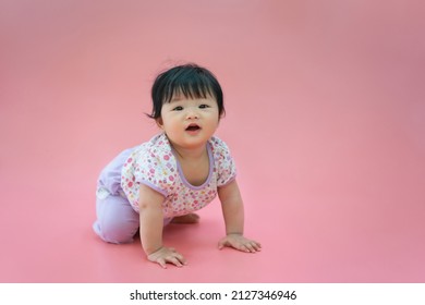 Asian Baby Smiling And Crawling On Pink Color Background. Cute 6 Months Baby Sitting With Copy Space Use As Concept Of Valentine, Love, Learn, Education, Baby Or Kid Department In Hospital.