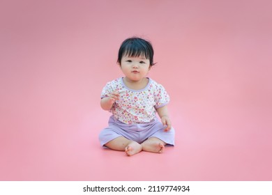 Asian Baby Smiling And Sitting On Pink Color Background. Cute 6 Months Baby Sitting With Copy Space Use As Concept Of Valentine, Love, Learn, Education, Baby Or Kid Department In Hospital.