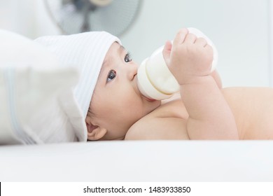 asian baby suck  milk from bottle and sleep on white bed