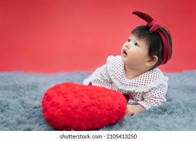 Asian Baby Valentine With Red Heart Crawling Red Background. Cute 6 Months Baby Crawling With Copy Space Use As Concept Of Valentine, Love, Baby Or Kid Department In Hospital.