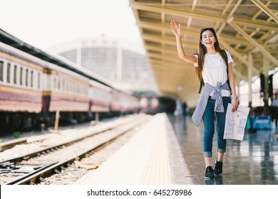 Asian Backpack Traveler Woman Holding Generic Local Map And Waving Hand At Train Station Platform, Summer Holiday Travelling Or Young Tourist Concept