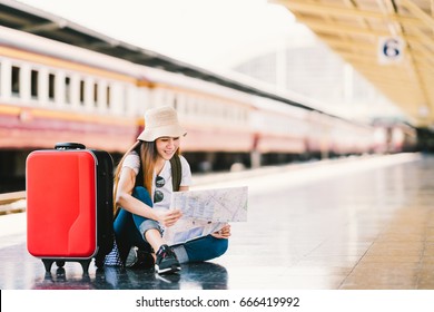 Asian backpack traveler woman using generic local map, siting alone at train station platform with luggage. Summer holiday traveling or young tourist concept