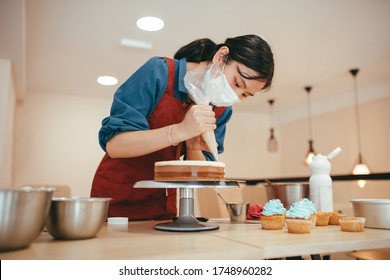 Asian Baker Decorating A Three-color Cake In Her Bakery.