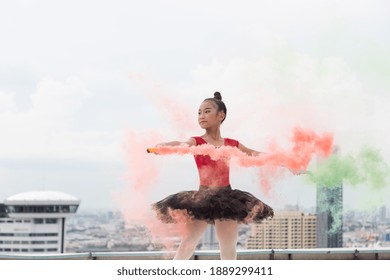 Asian ballerina ballet girl dancing with colour smoke on rooftop and skyscraper city view background. Female ballet dancer practicing dancing. Young ballerina ballet girl dancing - Powered by Shutterstock