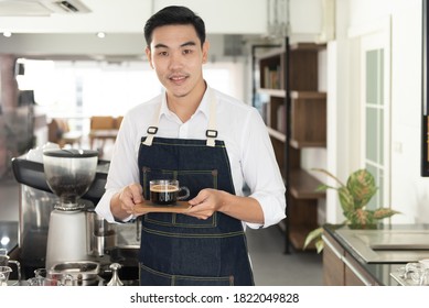 Asian Barista Man Holding A Cup Of Hot Black Coffee In The Coffee Shop