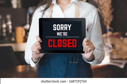asian barista shop owner holding tablet sign sorry we’re closed in front of counter bar. bankrupt business when coronavirus(covid-19) is outbreak in city - Shutterstock ID 1687192765