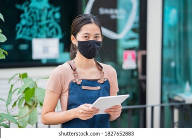 Asian barista woman worker new normal wearing facemask protection COVID-19 coronavirus pandemic using smart tablet device customer service serving food at café restaurant store small business owner - Powered by Shutterstock