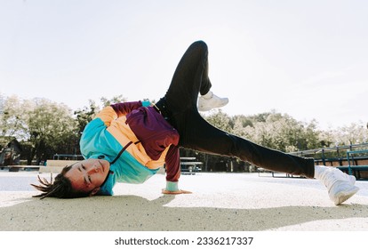 Asian b-boy performs breakdance trick - Stylish cool teen dancing at skate park