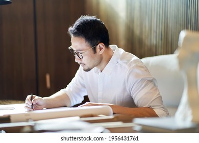 Asian bearded designer sitting, thinking and sketching ideas indoors - Powered by Shutterstock