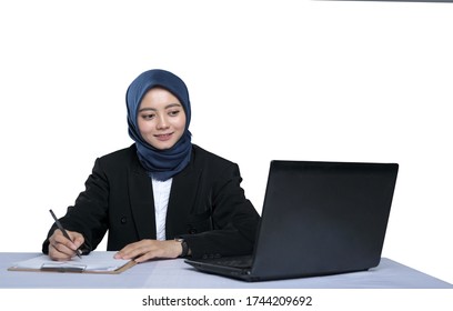 Asian Beautiful Business Woman In Hijab Writing On The Table Beside The Laptop