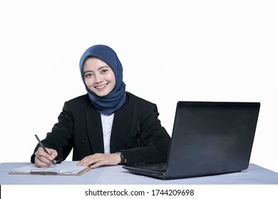 Asian Beautiful Business Woman In Hijab Writing On The Table Beside The Laptop