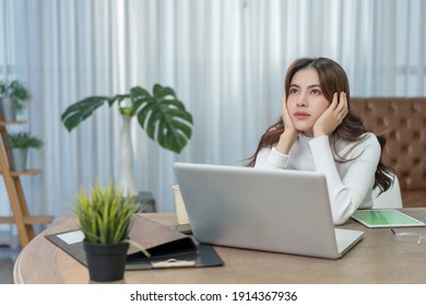 Asian Beautiful Business Woman Serious Moody Abstracted Thinking To Economy Crisis By Laptop To Financial Report And Investment. Successful Entrepreneur Work At Green Home Office Covid New Normal.