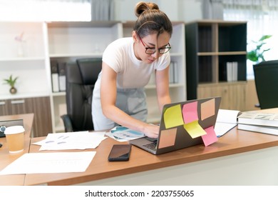 Asian Beautiful Business Woman Standing Thinking. Serious Female Professional Focus On Thinking About Information On Laptop And Put Pen On Face. Occupation Female Worker Think About Document She See.