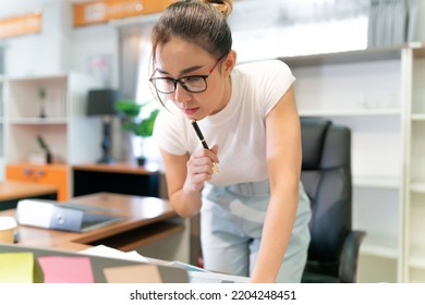 Asian Beautiful Business Woman Standing Thinking. Serious Female Professional Focus On Thinking About Information On Laptop And Put Pen On Face. Occupation Female Worker Think About Document She See.