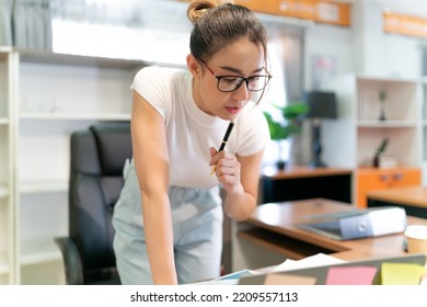 Asian Beautiful Business Woman Standing Thinking. Serious Female Professional Focus On Thinking About Information On Laptop And Put Pen On Face. Occupation Female Worker Think About Document She See.