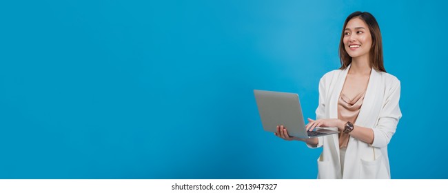 Asian beautiful businesswoman holding laptop in blue colour background with copy space.Concept of online business success with technology.