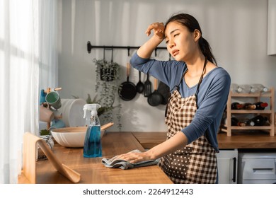 Asian beautiful cleaning service woman worker cleaning kitchen at home. Beautiful girl housewife housekeeper cleaner feel tired and upset while wiping dining table for housekeeping housework or chores