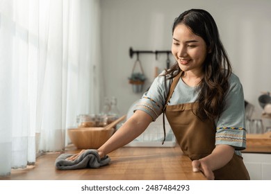 Asian beautiful cleaning service woman worker cleaning kitchen at home. Beautiful girl housewife housekeeper cleaner feel happy and wiping messy dirty dining table for housekeeping housework or chores - Powered by Shutterstock