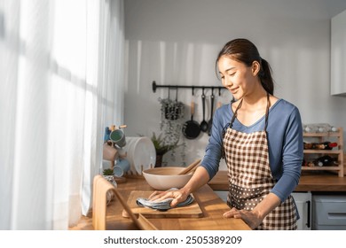 Asian beautiful cleaning service woman worker cleaning kitchen at home. Beautiful girl housewife housekeeper cleaner feel happy and wiping messy dirty dining table for housekeeping housework or chores - Powered by Shutterstock