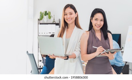 Asian Beautiful Empower Woman Holding Laptop And And Tablet With Friend Working At Meeting Room In Office.Owner Businesswoman Startup With Confident And Cheerful.