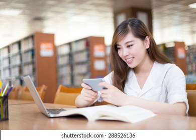 Asian beautiful female student using mobile phone in library - Powered by Shutterstock